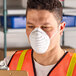 A person wearing a white general purpose nuisance dust mask with elastic straps.