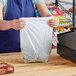 A woman holding a white plastic bag of groceries.