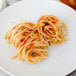 A plate of Regal linguine with tomato sauce on a white surface.