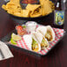 A plate of tacos and chips served on a red and white checkered HS Inc. square deli server.