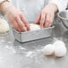 A person's hands kneading dough in a Chicago Metallic bread loaf pan.