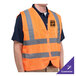 A man wearing a Cordova orange high visibility safety vest with reflective strips.