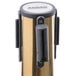A brass Aarco crowd control stanchion with a black metal cylinder.