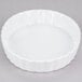 A white fluted oval serving dish with a white surface and ruffled edge.