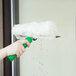 A hand using a green Unger window squeegee with white background.