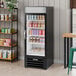 A black glass door merchandiser refrigerator with a white interior, stocked with various beverages and food items.