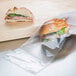 a person holding a sandwich in a plastic bag