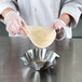 A person in a white coat holding a tortilla over a Chicago Metallic Tortilla Shell Pan.