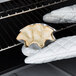 A person using oven mitts to remove tortilla shell pans from the oven.