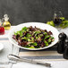 A 10 Strawberry Street Whittier white porcelain coupe bowl filled with salad on a table.