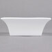 An Arcoroc white square flared bowl on a gray surface.