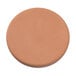 A round tan warming stone with a shadow.