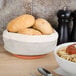 A bowl of spaghetti and bread in a basket on a table.
