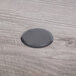 A black circular object on a wood surface with a grey plate.