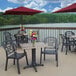 A Grosfillex Aged Oak square table top with a red umbrella and flowers on a deck.