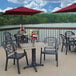 A Grosfillex rectangular Aged Oak table top on an outdoor patio with a red umbrella and flowers on it.