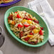 A Tuxton Cilantro oval china platter with a plate of pasta with tomatoes and chicken.
