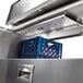 A metal drawer with blue plastic dividers inside a Traulsen school milk cooler.