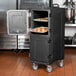 A Carlisle black food pan carrier with trays of food inside.