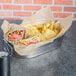 EcoCraft deli wrap covering a metal container with a sandwich and chips inside.