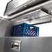 A metal drawer with a blue plastic shelf and a blue grid inside a Traulsen school milk cooler.