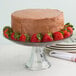 An Anchor Hocking tiered glass platter with a chocolate cake and strawberries on top.