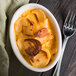 An ivory Hall China oval baker filled with potato casserole with a fork.