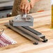 A hand using an Edlund griddle scraper sharpener to sharpen a blade.