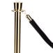A black rope with gold ends attached to a gold stanchion pole.