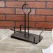 A black metal Tablecraft Marbella rack with two metal rods on a wood surface.