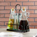 A Tablecraft Marbella metal rack with glass containers holding oil and vinegar.