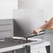 A person using a stainless steel splash guard to clean a fryer.