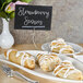 A plate of pastries on a table with American Metalcraft double-sided sign clips holding table cards.