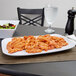 A white Siciliano rectangular platter with pasta and salad on a table.