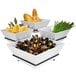 A black Cal-Mil display organizer with white square bowls filled with food.