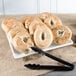 A Cal-Mil white melamine square platter with bagels and a knife on it in a bakery display.