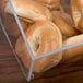 A clear container with bagels in a Cal-Mil bakery display case.