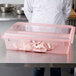 A chef in a white coat standing in front of a large red Carlisle food storage box.