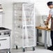 A tall, clear disposable plastic cover placed over a bun pan rack in a commercial kitchen.