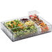 A clear plastic container with a variety of food on a counter in a salad bar.