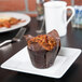 A Tuxton TuxTrendz Santorini bright white china plate with a muffin on it next to a cup of coffee on a table.