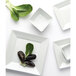 A close-up of a white square bowl with a leaf on it.