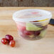 A translucent plastic Pactiv DELItainer filled with fruit on a table.