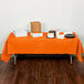 A Sunkissed Orange Creative Converting table cover on a table with food.