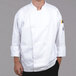 A man wearing a white Chef Revival long sleeve chef jacket with chef logo buttons.