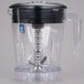 A Waring clear copolyester blender jar with a black lid on a blender.