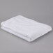 A folded white Oxford Signature bath towel on a gray surface.