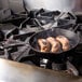 A Lodge cast iron skillet with sausages cooking in it on a stove.