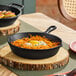 An 8-inch pre-seasoned cast iron skillet with a handle, shown on a wooden serving board.