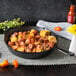 A Lodge cast iron skillet filled with food including corn and sausage on a table.